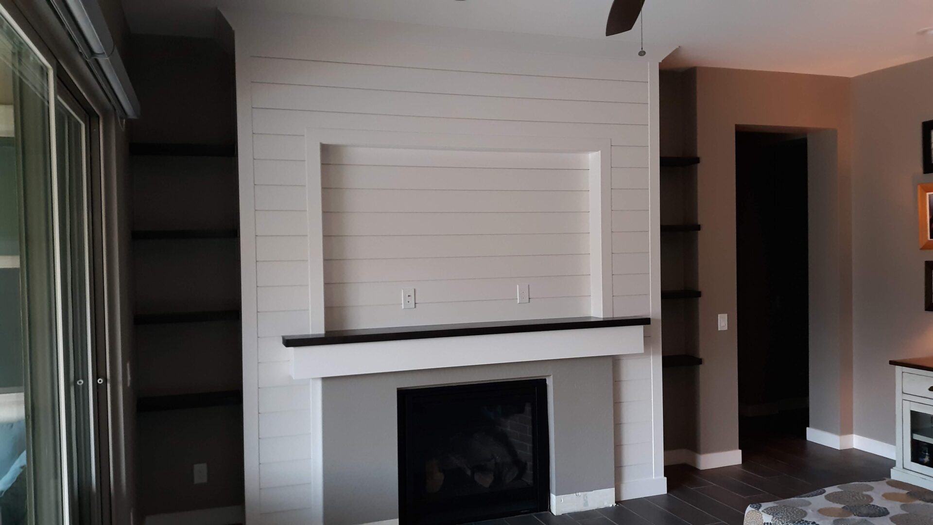 A fireplace with a mantle and built in shelves.