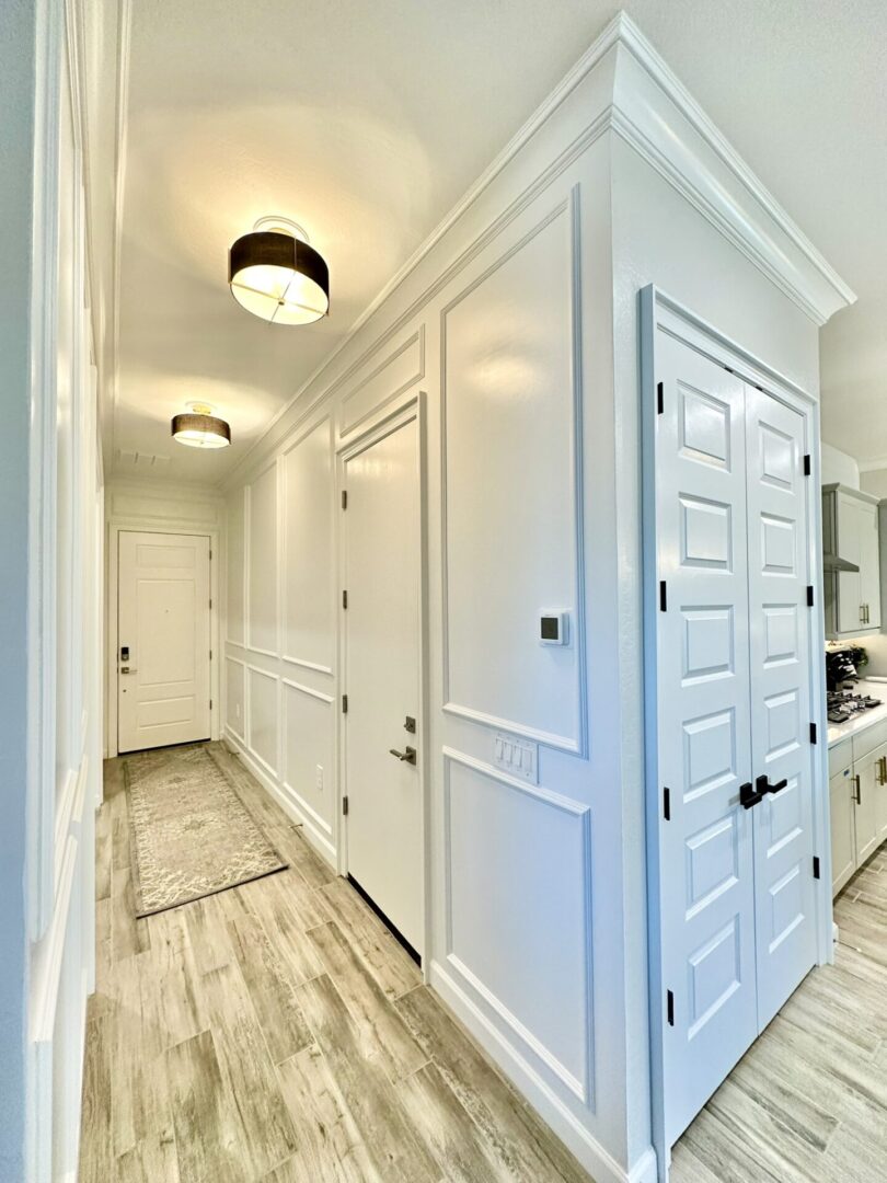 A hallway with two doors and a mirror.