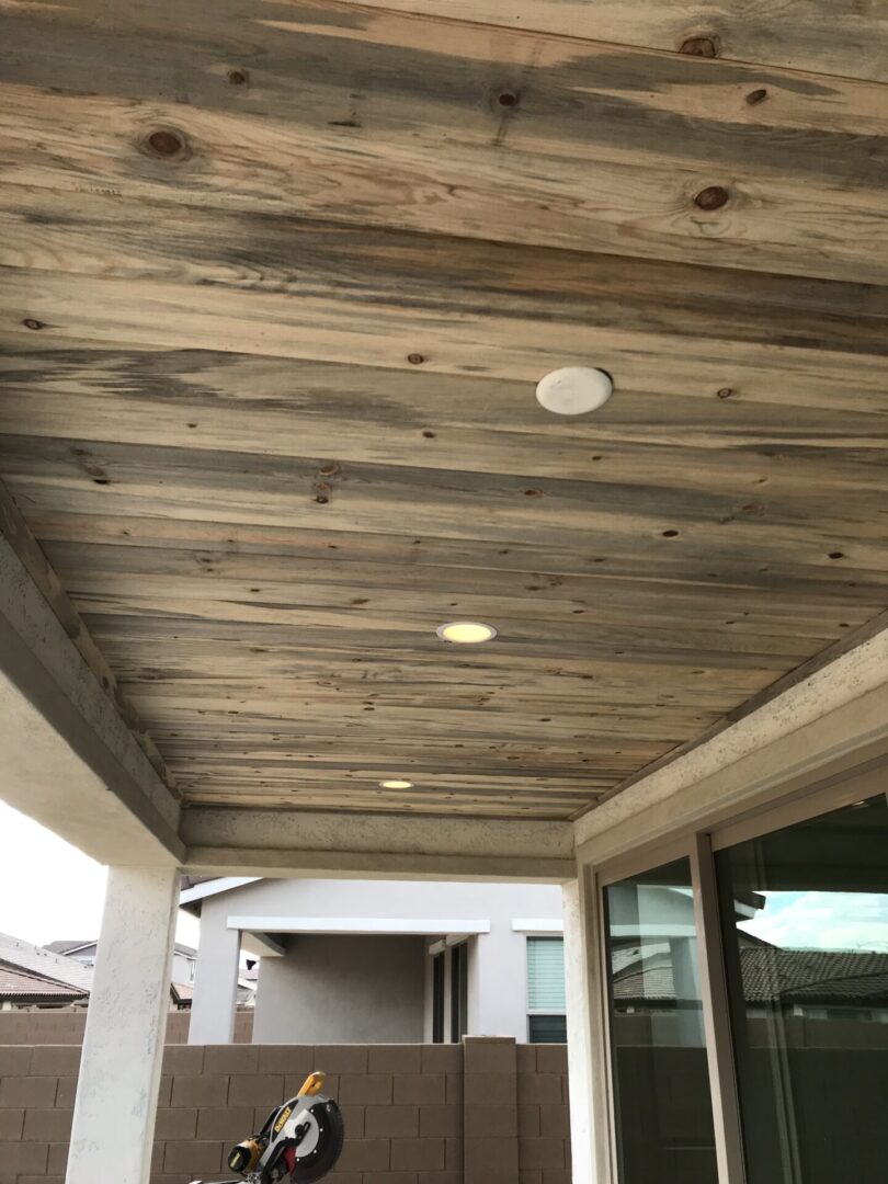 A porch with wood ceiling and white lights.