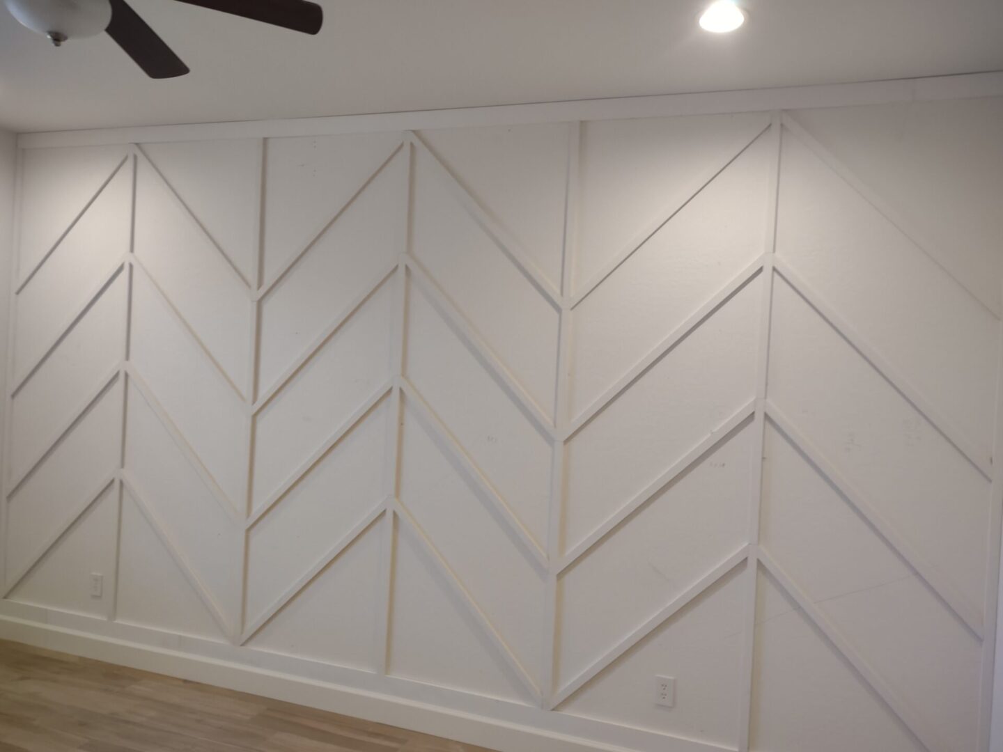 A white wall with wooden chevron pattern on it.
