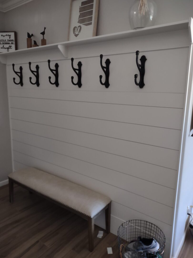 A bench with hooks on the wall above it