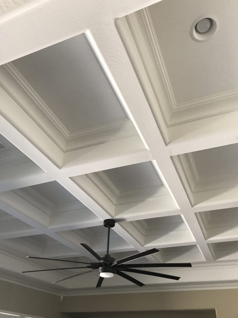 A ceiling with white panels and a black fan.