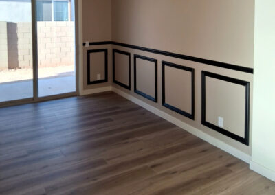 White baseboards beneath black picture frame wall moulding in a finished room.