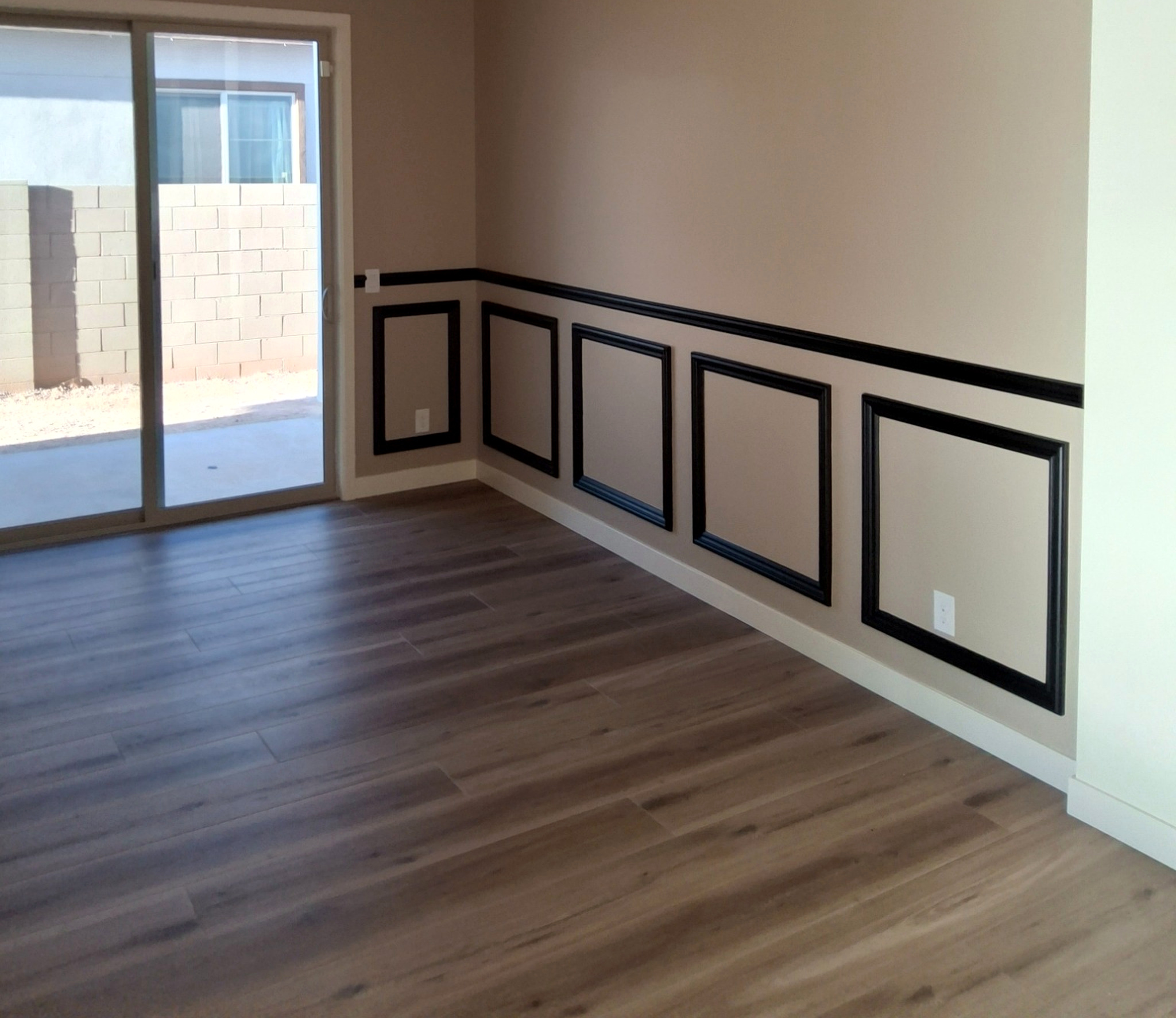 White baseboards beneath black picture frame wall moulding in a finished room.