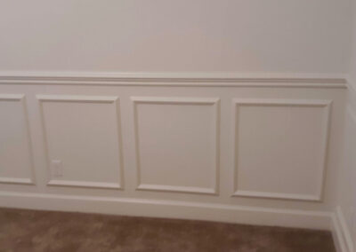White baseboard moulding wrapping an inside corner beneath raised wall panels.
